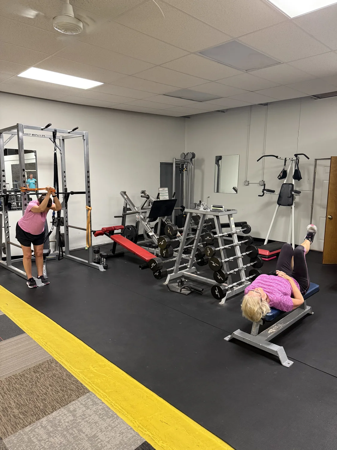 Clients exercising with strength training equipment inside the studio